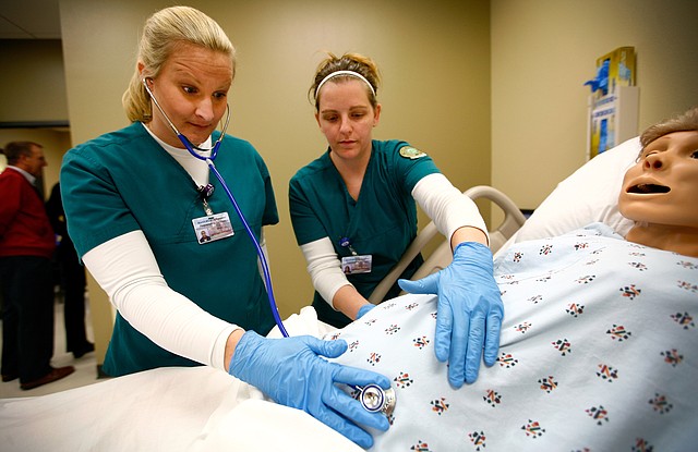Shelly Lee, left, of Fayetteville and Jessica Abramson of Springdale check Friday on a pregnant dummy at the Center for Health Professions building at NorthWest Arkansas Community College in Bentonville. The school held a grand opening ceremony for the 83,000-square-foot building. Classes began in the new building Monday.
