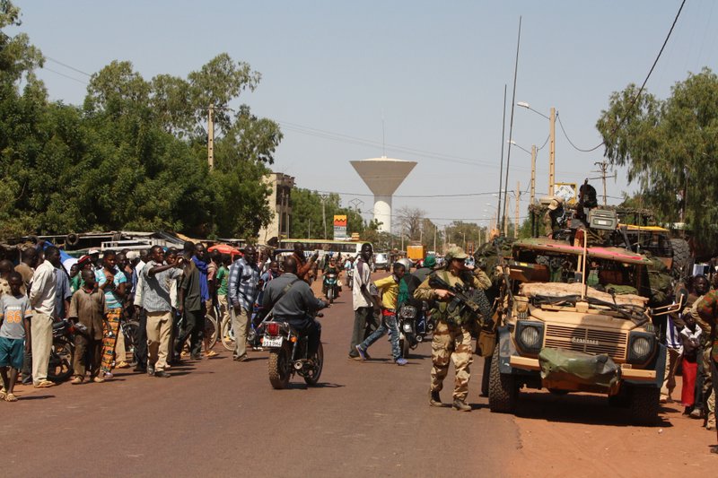 Residents of San in central Mali gather to look on as French troops pass through en route to Sevare, Mali, Friday, Jan. 18, 2013. French forces encircled a key Malian town on Friday to stop radical Islamists from striking closer to the capital, a French official said. The move to surround Diabaly came as French and Malian authorities said they had retaken Konna, the central city whose capture prompted the French military intervention last week