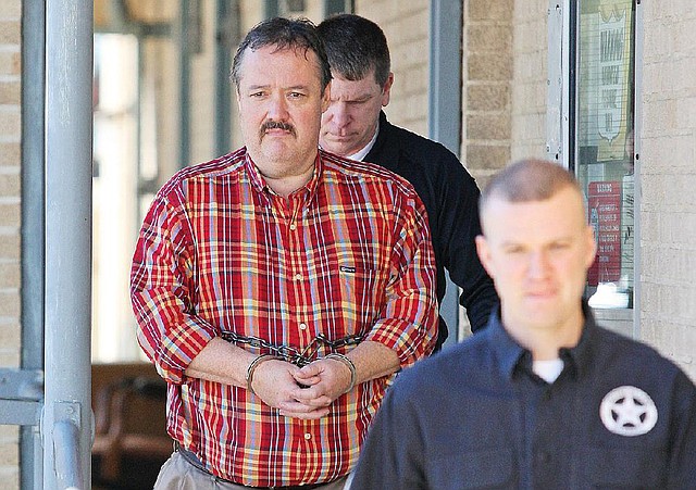 Ouachita County Judge Mike Hesterly is escorted Friday from the federal courthouse in El Dorado. 