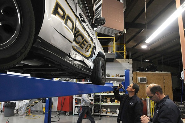 Tony Anderson, left, mechanic with the Springdale Police Department, and Jeff Bohannan, fleet manager with the department, look over damage Friday to a Chevrolet Tahoe damaged in an accident. Besides external damage to the vehicle, lines leading to the rear air conditioner were pinched causing them to leak. Bohannan and Anderson drained the refrigerant from the system for safety. 