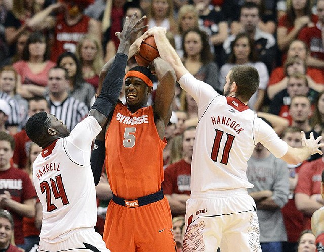 Syracuse forward C.J. Fair (5) tries to pass out of a double-team set by Louisville’s Montrezi Harrell (24) and Luke Hancock during the second half of the No. 6 Orange’s 70-68 victory over the top-ranked Cardinals on Saturday in Louisville, Ky. 