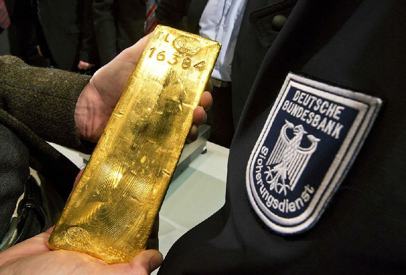 A gold ingot is held close to a German Central Bank security guard last week as the bank announced it will return to Germany 374 tons of gold being stored in France and another 300 tons being stored in the United States by 2020.