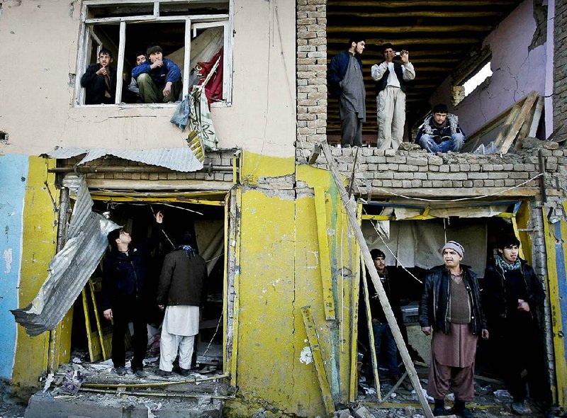 Afghans watch from a damaged building across from Kabul traffic police headquarters building Monday that was attacked by militants in Kabul. 
