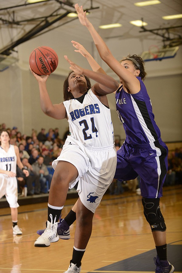 Rogers’ Taylor Strickland, left, takes the ball to the basket under pressure from Fayetteville’s Vanessa Matlock during the Lady Mounties’ game Jan. 11 against the Lady Bulldogs at King Arena in Rogers. Strickland has scored 119 points total points in the Lady Mounties’ past four games. 