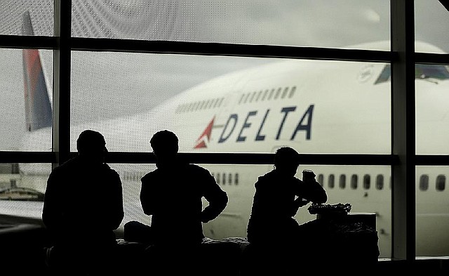 FILE - In this Monday, Oct. 29, 2012, file photo, travelers on Delta Airlines waits for flights, in Detroit. Delta said Superstorm Sandy hurt fourth-quarter profits by $100 million in 2012. That, plus special charges, left Delta Air Lines Inc. with a profit of just $7 million.  (AP Photo/Charlie Riedel, file)