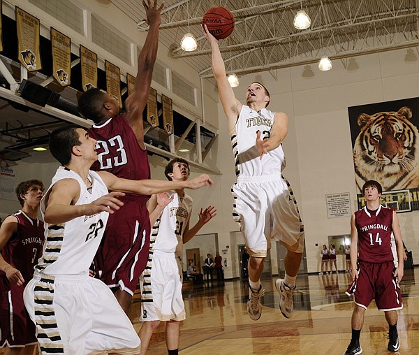 Bentonville’s Austin Heard takes the ball to the basket over Springdale’s Brendan Cook during the Tigers’ game Tuesday at Tiger Arena in Bentonville. 