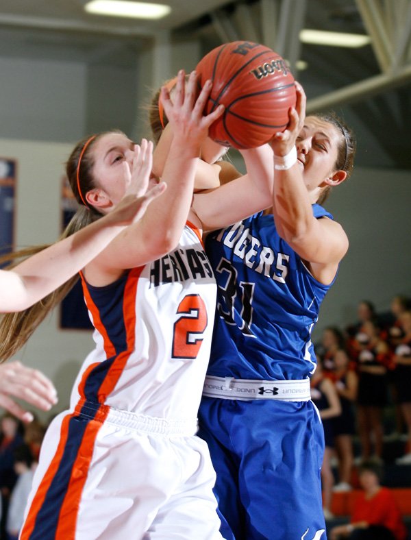 Ashley Ward, left, a Rogers Heritage senior, and Rogers High senior McKinzie James vie for a rebound during the first half on Tuesday at Rogers Heritage. 