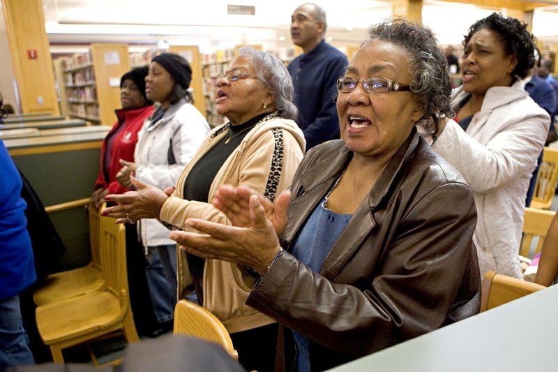 Cora Lewis sings and claps during a program Monday honoring Martin Luther King Jr. at the Faulkner County Library. The program followed a unity march that began at City Hall.