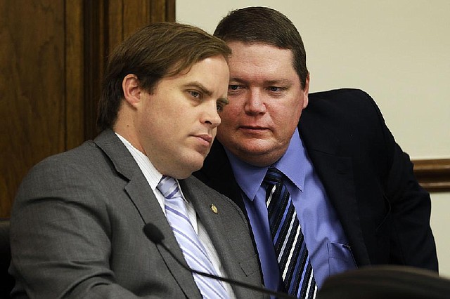 State Sens. Jon Woods (left), R-Springdale, and Bryan King, R-Green Forest, talk Wednesday at a Senate Judiciary Committee meeting during which the panel approved King’s bill to end the ban on concealed handguns in churches. 