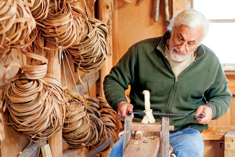 Owen Rein makes chairs and baskets using traditional tools at his home in the woods near Mountain View. He’s known for his rocking chairs made from trees that he cuts on his property. Rein uses a draw knife to fashion parts for a chair.