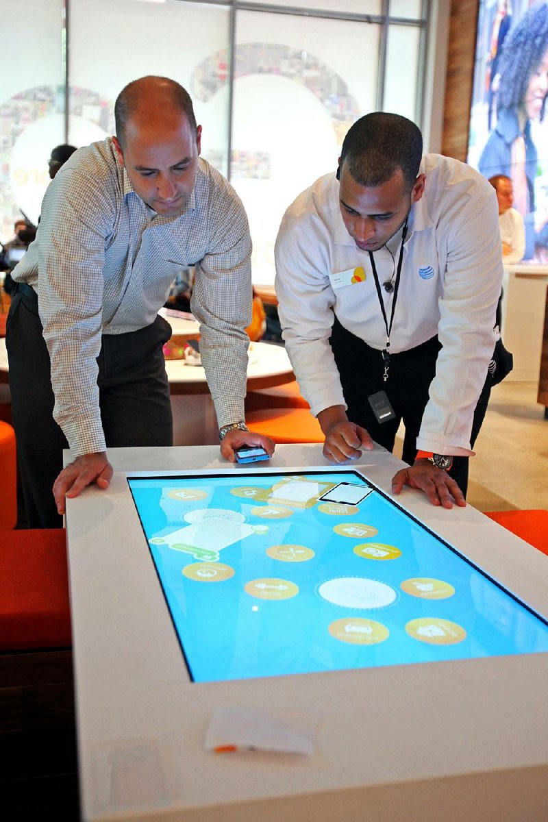 An AT&T salesman demonstrates a mobile phone at an AT&T store in Chicago. AT&T has agreed to buy the rights to airwaves from Verizon Wireless to bolster its network. 