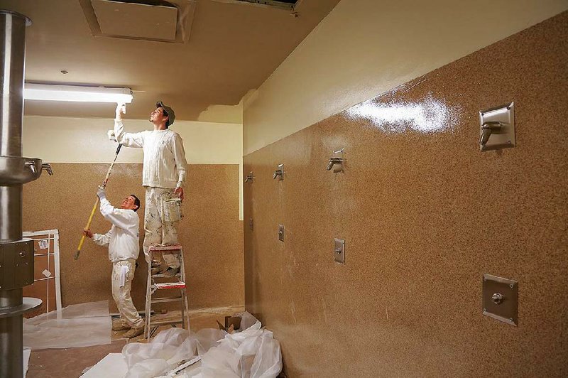 Brothers George Zavala (left) and Carlos Zavala paint the ceiling of a shower room Friday in the Union Rescue Mission’s Nehemiah House, under construction on Confederate Boulevard in Little Rock. The facility will house substance-abuse and transitional work programs and a transient lodge for men. 