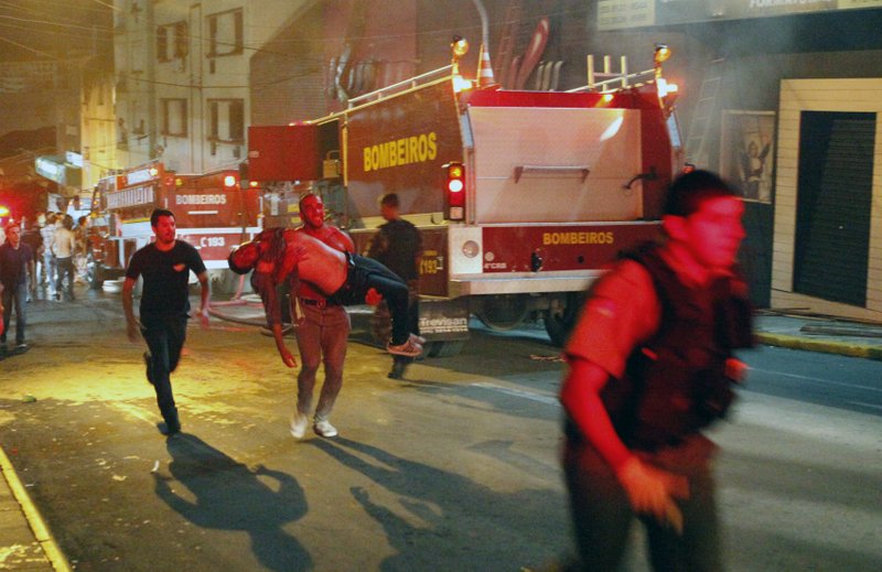 A man carries an injured victim of a fire at the Kiss club in Santa Maria city, Rio Grande do Sul state, Brazil, early Sunday, Jan. 27, 2013. Firefighters say that the death toll from a fire that swept through a crowded nightclub in southern Brazil has risen to 180. Officials say the fire broke out while a band was performing. At least 200 people ere also injured.