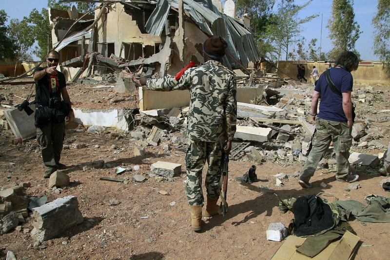 In this image taken during an official visit organized by the Malian army to the town of Konna, some 430 miles north of Mali's capital Bamako, Saturday, Jan. 26, 2013, a Malian soldier gestures at journalists to leave the area of a French air strike.