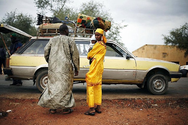A Malian family’s taxi is searched at a checkpoint Sunday on the Gao road outside Sevare, Mali. 