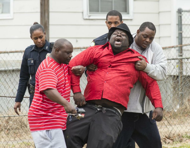 An unidentified man is pulled away screaming from a crime scene at 2014 W. 18th St. in Little Rock where Joseph McCardell, 38, was found inside his house dead from a gunshot Sunday afternoon. The unidentified man tried to break through the police tape to get into the house, but police restrained him until he was led away by friends.