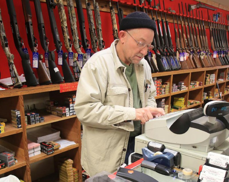 Ron Brown rings up a sale earlier this month for a customer who bought several ammunition magazines for AR-15 and AK-47 assault rifles at Don’s Weaponry in North Little Rock. 