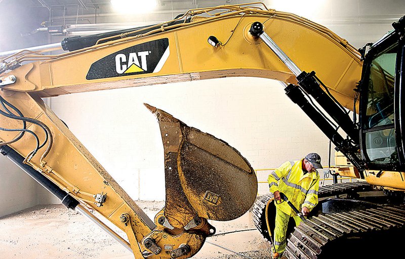 A mechanic power washes a Caterpillar Inc. excavator before it is serviced at a Caterpillar dealership in Bettendorf, Iowa. 