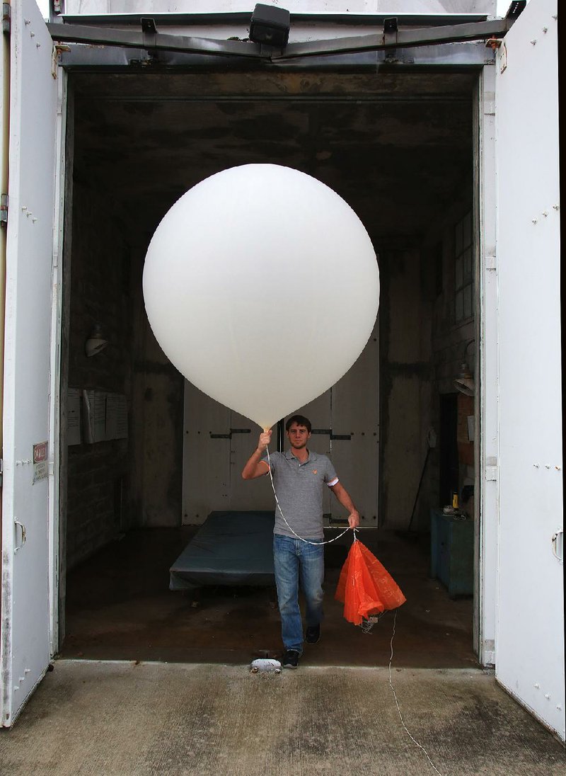 Matthew Clay, a meterologist interning at the National Weather Service in North Little Rock, brings a weather balloon out of a building so it can be released Tuesday. It was not a scheduled release, but they wanted more data on the current weather conditions which may include heavy storms.
