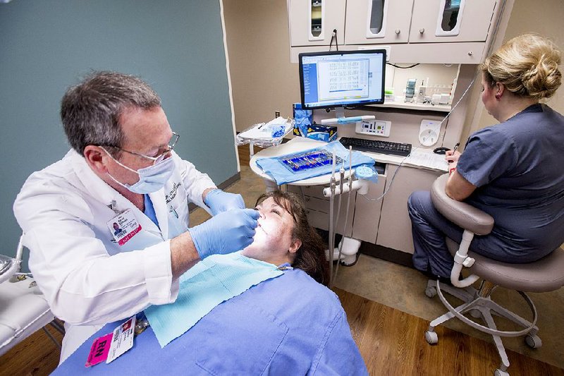  Dr. David Stillwell, director of the clinical and residency programs in the Center for Dental Education at UAMS examines Shelly Crouses teeth during a comprehensive exam as Tiffany London, lead dental technician takes notes at a new oral health clinic which opened Monday at UAMS. The Delta Dental of Arkansas Foundation contributed a total of $2 million toward the new Oral Health Clinic where future plans include starting the only dental residency program in Arkansas, which will allow dental school graduates to complete advanced dental education and hopefully continue their careers in the state.  The clinic will offer oral health services including: crowns, dentures, fillings, root canal therapy and hygiene services.
 