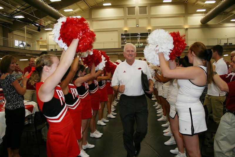 Former University of Arkansas football coach and athletic director Frank Broyles, center, runs between lines of Heber Springs cheerleaders during a recent gathering of the Greers Ferry Lake Area Razorback Club. The group is the newest Razorback club in the state and didn’t form without some resistance.