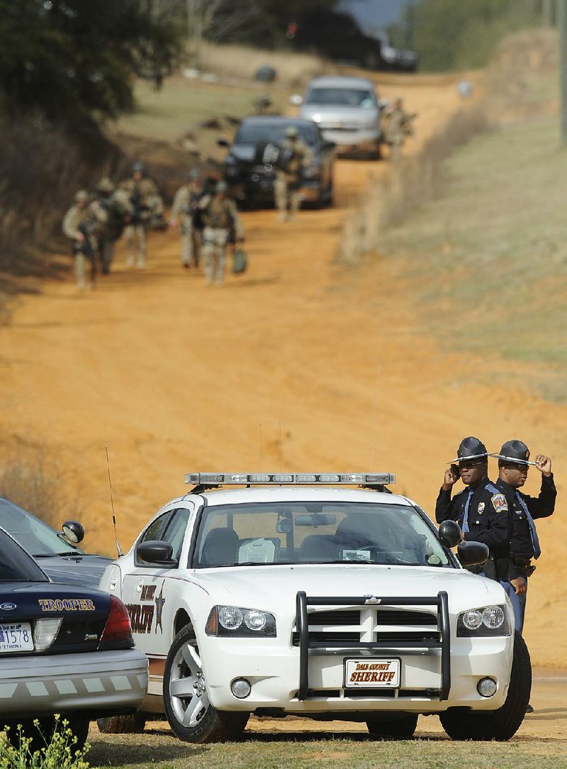 Police SWAT teams and hostage negotiators are gathered at standoff and hostage scene in Dale County near Midland City, Ala. on Wednesday Jan. 30, 2013. Authorities were locked in a standoff Wednesday with a gunman authorities say on Tuesday intercepted a school bus, killed the driver, snatched a 6-year-old boy and retreated into a bunker at his home in Alabama. (AP Photo/Montgomery Advertiser, Mickey Welsh) (AP Photo/The Montgomery Advertiser, Mickey Welsh)