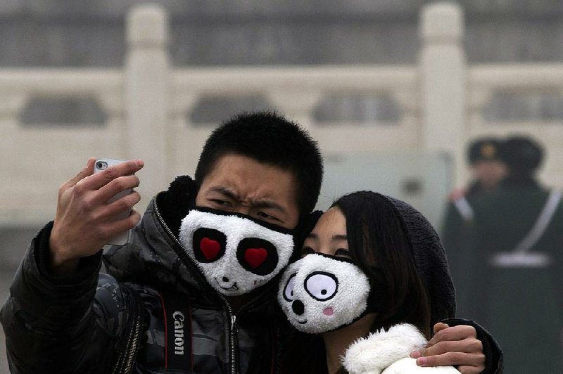 A couple wearing protective masks poses for a self portrait in thick haze on Tiananmen Square in Beijing Tuesday, Jan. 29, 2013. Extremely high pollution levels shrouded eastern China for the second time in about two weeks Tuesday, forcing airlines in Beijing and elsewhere to cancel flights because of poor visibility and prompting government warnings for residents to stay indoors. (AP Photo/Ng Han Guan)