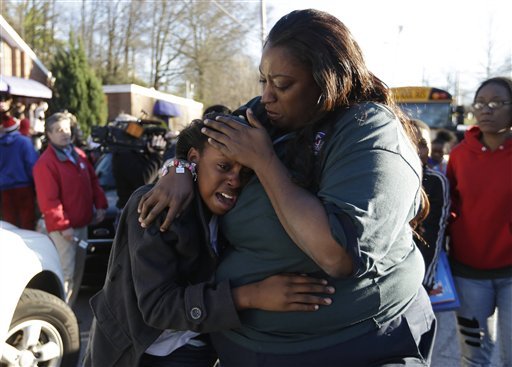 A woman comforts a child after after a shooting at an Price Middle school in Atlanta Thursday, Jan. 31, 2013. A 14-year-old boy was wounded outside the school Thursday afternoon and a fellow student was in custody as a suspect, authorities said. No other students were hurt. 