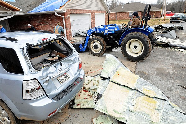 Kody Krummel operates a tractor as crews clean up damage at a duplex next to an orthodontist office in Elkins on Wednesday. A tornado passed through parts of the town Tuesday evening, destroying the roof of the office and throwing debris onto nearby homes. 