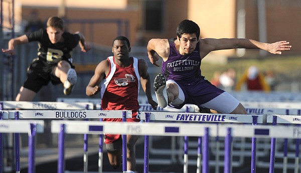 Jorge Gonzalez, right, of Fayetteville clears a hurdle March 9 during the 110-meter hurdles in the annual Bulldog Relays at Harmon Field in Fayetteville. 