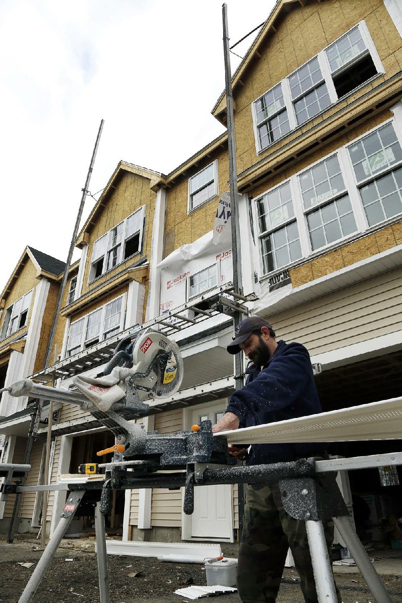 A builder works on condominiums in North Andover, Mass. Spending on construction projects rose to $885 billion in December, the Commerce Department said Friday. 