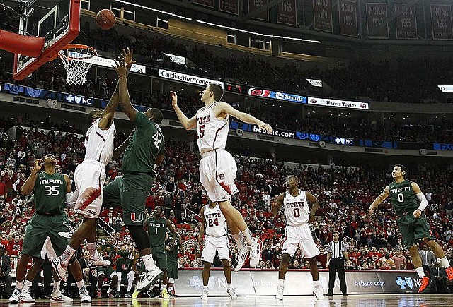 Miami's Reggie Johnson (42) taps in the game-winning shot over North Carolina State's Richard Howell and Scott Wood (15) as time expires during the second half of an NCAA college basketball game in Raleigh, N.C., Saturday, Feb. 2, 2013. Miami won 79-78. Miami's Kenny Kadji (35) looks on at left. (AP Photo/Gerry Broome)