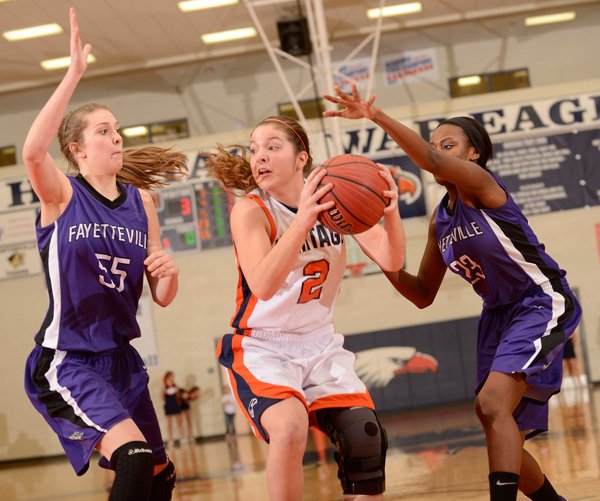 Ashley Ward, center, of Rogers Heritage looks to pass the ball Friday under pressure from Fayetteville’s Lauren Schuldt, left, and Alexa Howard during the game at War Eagle Arena in Rogers. 