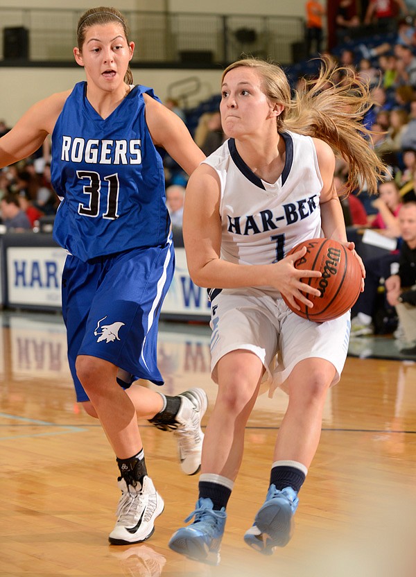 McKinzie James of Rogers High drives past Springdale High’s Javonda Daniels on Friday at King Arena in Rogers. 