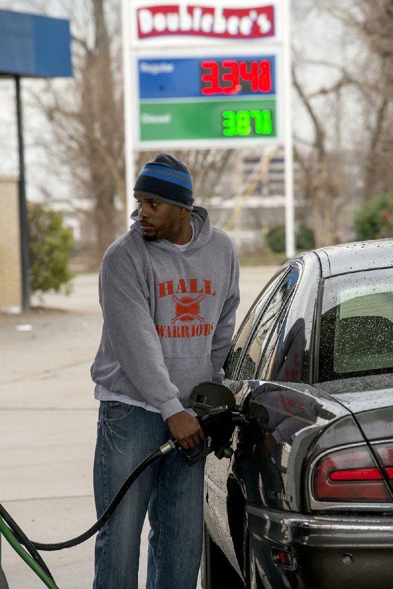 Keith Gleason fills his car’s tank at an Exxon station on Cantrell Road in Little Rock on Monday. 