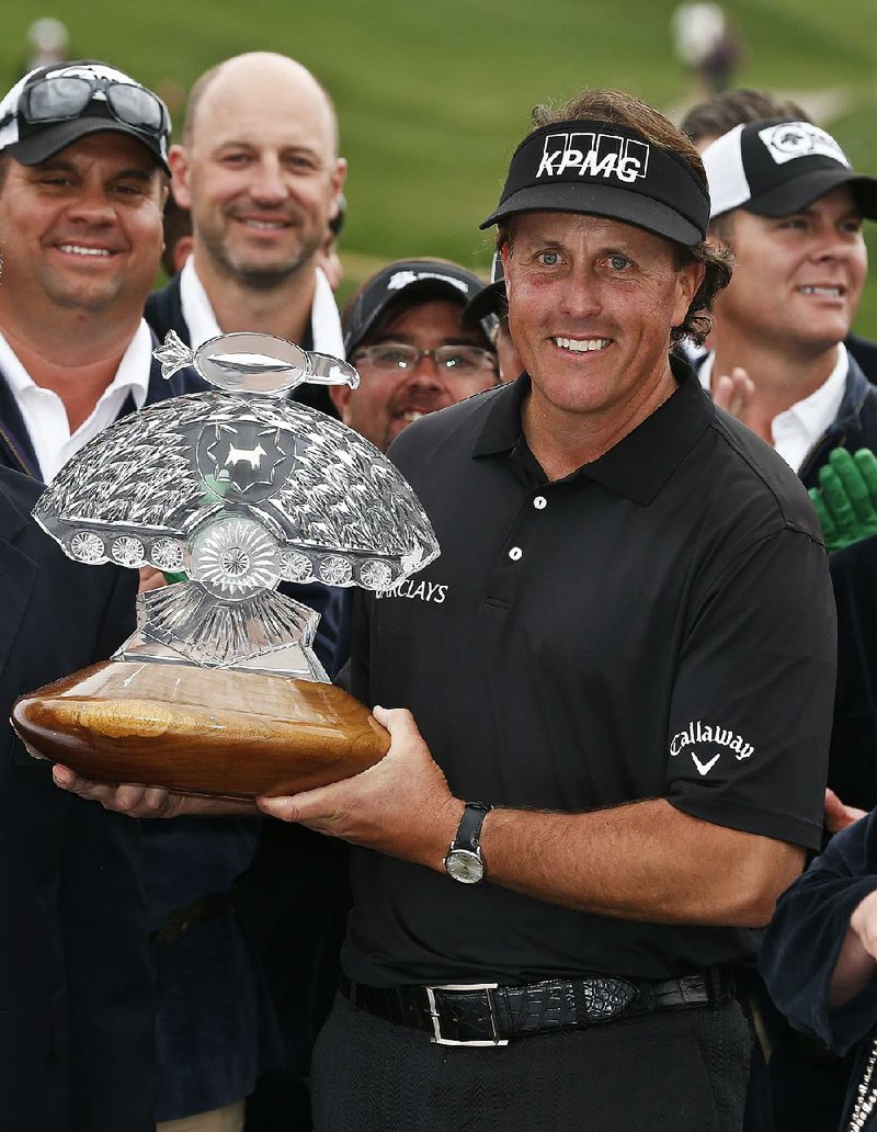Phil Mickelson holds the Phoenix Open trophy Sunday afternoon. Mickelson shot a final-round 4-under-par 67 to finish at 28-under 256, two strokes off the PGA Tour record of 254 set by Tommy Armour III in the 2003 Texas Open. 