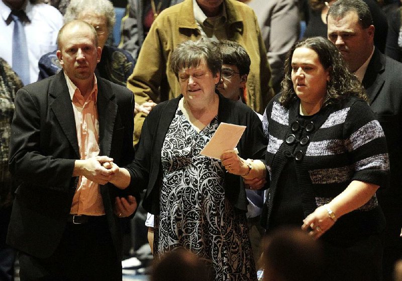 Jan Poland (center) walks with her son Aaron and daughter Lydia as they join friends and family to pay respects to Charles Albert Poland Jr. on Sunday at the Ozark Civic Center in Ozark, Ala. 