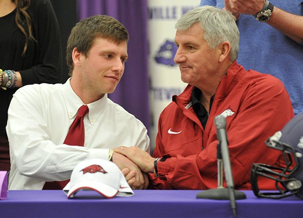Fayetteville High's Austin Allen shakes hands with his father Bobby Allen after signing his letter of intent to play football at the University of Arkansas during the official signing ceremony Wednesday, Feb. 6, 2013, at Fayetteville High School. 