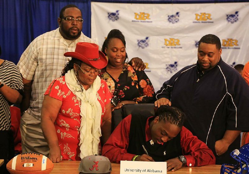 Altee Tenpenny signs a letter of intent Wednesday at North Little Rock High School gym to play for the University of Alabama.  Joining him are (left to right) Lee Shepard, his stepdad, grandmother Barbara Sims, Shenitta Shepard, his mother and Derek Tenpenny, his dad.