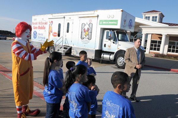 Daniel Barnes, right, chairman of Ronald McDonald House Charities of Arkoma, talks Wednesday about the Ronald McDonald Care Mobile at Harp Elementary School in Springdale. The mobile dental unit is celebrating its third year and providing more than $1 million in dental care to students in Washington and Benton counties. 