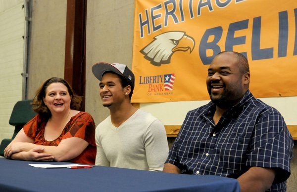 Forrest Johnson, center, a Rogers Heritage wide receiver, laughs with his parents, Tracy, left, and Lee Johnson, on Wednesday during a letter of intent signing ceremony at the school. Forrest Johnson plans to play football for Henderson State University next season. 