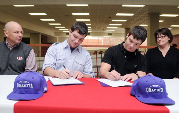 Shane Patrick, left, and Melissa Patrick, right, smile as their sons, Jay Patrick, left center, and Clay Patrick sign letters of intent Wednesday at Springdale High. The brothers signed to play football for Ouachita Baptist University in Arkadelphia. 