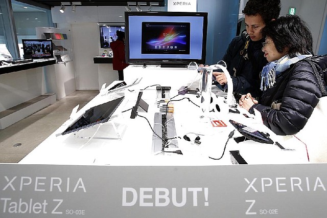 Shoppers examine Sony tablet computers displayed Thursday at the company’s showroom in Tokyo. Sony on Thursday reported a $115 million quarterly loss. 