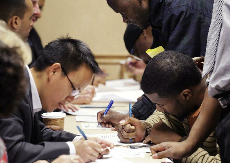 Job seekers complete applications at a job fair Wednesday sponsored by Swissport in Newark, N.J. Fewer Americans sought unemployment benefits last week, the Labor Department said Thursday. 