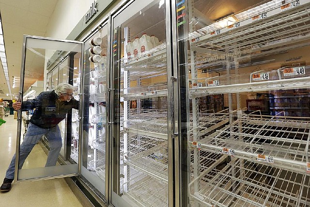Jack Percoco of Cambridge, Mass., reaches into depleted shelves for milk Friday at a supermarket in Somerville, Mass. A major winter storm heading toward the U.S. Northeast was expected to drop 1-3 feet of snow on the Boston area. 