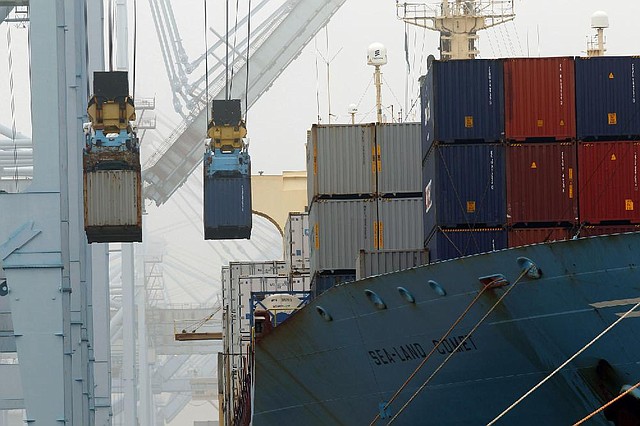 Containers are unloaded from cargo ships at APM Terninals in the Port of Los Angeles. The Commerce Department reported that the trade deficit fell nearly 21 percent in December as exports rose and imports shrank. 