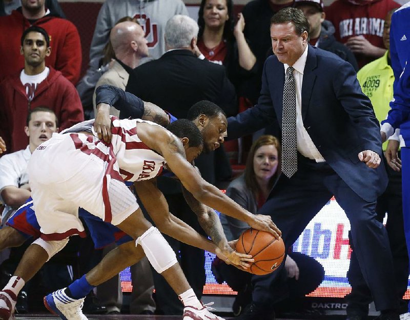 Kansas Coach Bill Self (right) watches as Kansas guard Naadir Tharpe and Oklahoma guard Je’lon Hornbeak (front) battle for a loose ball during the second half of the No. 5 Jayhawks’ 72-66 loss to the Sooners on Saturday in Norman, Okla. 