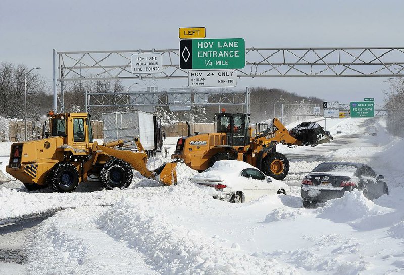 Payloaders clear snow from the Long Island Expressway just west of exit 59 Ocean Ave where several cars and a truck are abandoned after a snow storm on Saturday, Feb. 9, 31, 2013, in Ronkonkoma , N.Y. (AP Photo/Kathy Kmonicek)