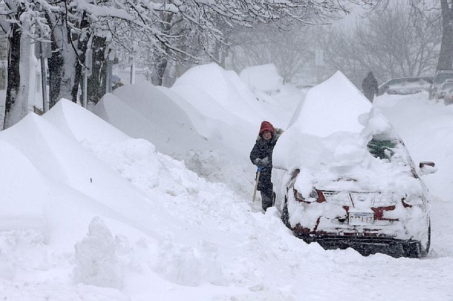 A woman shovels snow to clear out a car on Third Street in the South Boston neighborhood of Boston on Saturday, Feb. 9, 2013. A behemoth storm packing hurricane-force wind gusts and blizzard conditions swept through the Northeast overnight. (AP Photo/Gene J. Puskar)