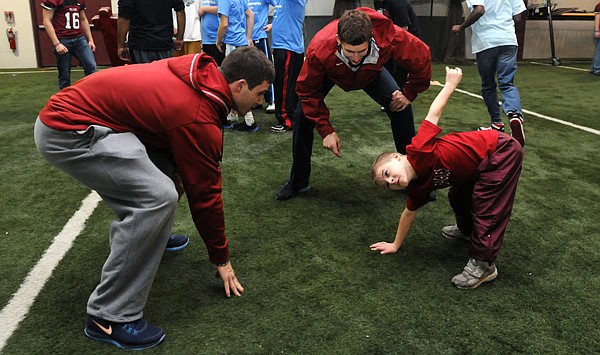 Noah Kittelson, center, counts down as Kevin Lazas, left, and Andy Turnbow, 9, a Special Olympics athlete from Huntsville, get in a three-point stance Thursday during a football clinic hosted by the Springdale High football team at the indoor field house at Springdale High School. Kittelson and Lazas, both track and field athletes at the University of Arkansas, volunteered to help at the event. The Springdale football team hosts the clinic annually for Special Olympics athletes. The team was expecting more than 300 Special Olympics athletes from around the state to participate in the event.